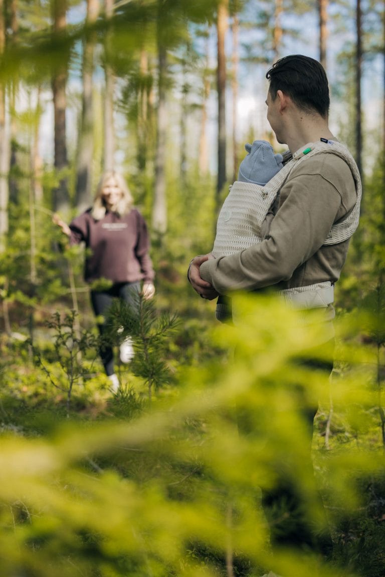 Perhe metsässä vauvan kanssa.