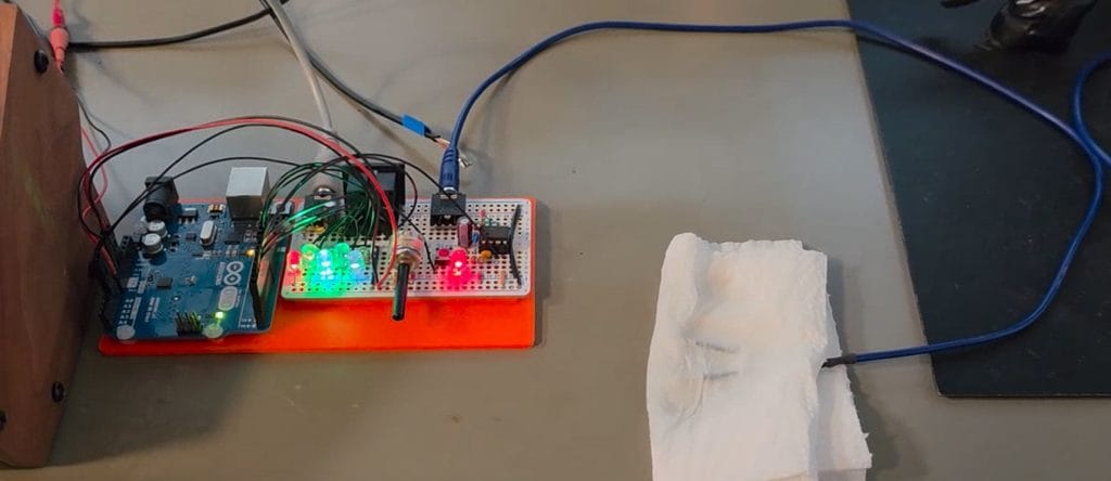Technical gadget with switches and wires. One of the wires go inside wet white paper towel.
