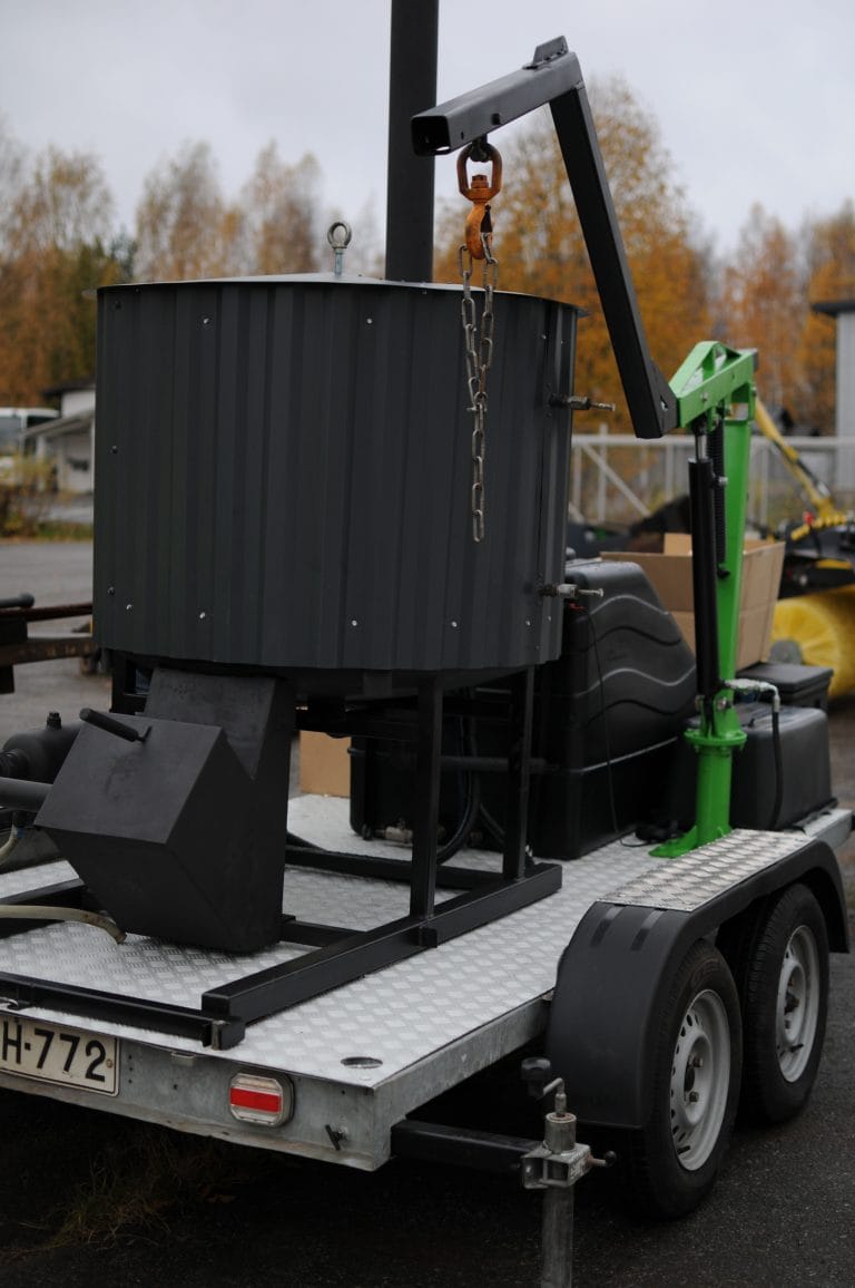 Peräkärryn päälle asennettu siirrettävä pyrolyysilaite, jossa sylinterimäinen retortti ja nostopuomi ketjuineen.