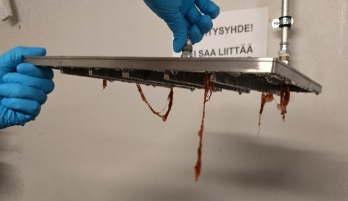 Valokuva seulasta, jonka alla roikkuu punaisia rihmoja.
